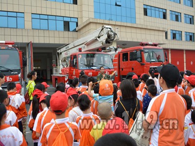 图为讲解员为小记者讲解消防车